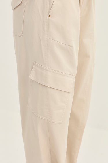 Close-up of a pair of light beige cargo pants by Verge showing the side pocket and fabric texture against a plain white background.