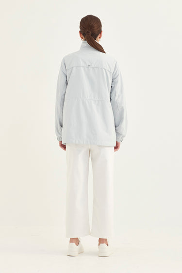A model shown from the back wearing a light gray utility jacket, white wide-leg cropped pants by Verge, and white sneakers against a plain white studio background.