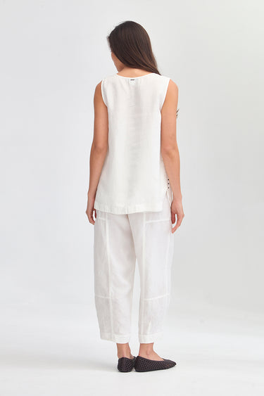 A woman shown from the back wearing a sleeveless white linen top and matching white linen pants by Verge, paired with black pointed flats, against a light gray studio background.