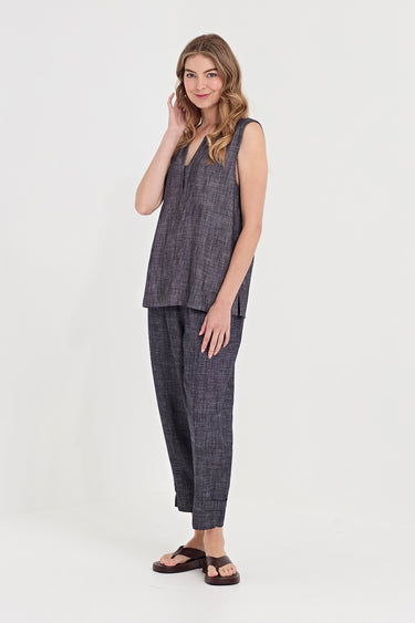 A woman modeling a matching sleeveless top and wide-leg pants set in a dark gray textured fabric by Verge, paired with dark brown sandals, against a plain white studio background.