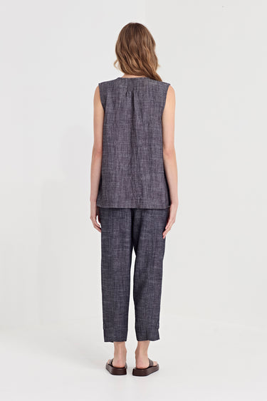 A woman viewed from the back wearing a sleeveless textured tank top and matching cropped trousers in a dark gray and black woven pattern by Verge, paired with dark brown flat sandals, against a plain white studio background.