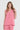 A woman modeling a sleeveless pink linen top by Verge and matching pants against a light gray studio background.