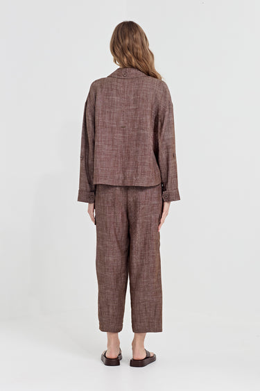 A woman viewed from the back wearing a matching brown tweed cropped jacket and cropped trousers set by Verge, paired with dark brown flat sandals, against a plain white studio background.