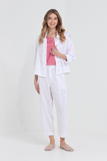 A woman modeling a white cropped button-up shirt jacket, white wide-leg cropped pants, and a pink ribbed tank top by Verge, styled with beige flat sandals against a light gray studio background.